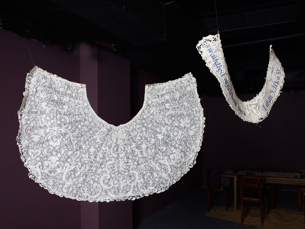 Installation modern art of of two antique lace half circles with contemporary thoughts embroidered.