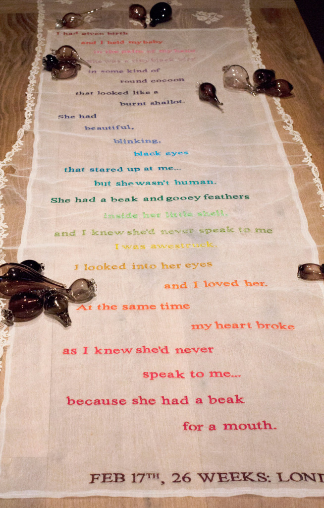Installation art: antique lace with rainbow colored seams displaying a pregnancy dream poem.